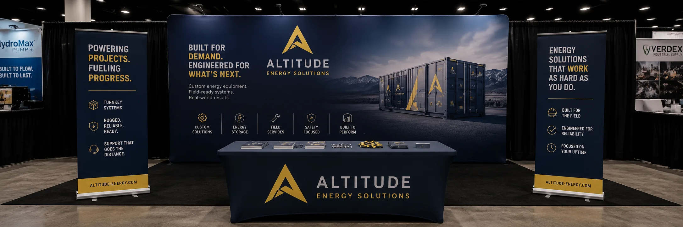 An energy company's tradeshow booth: dark printed backdrop wall, two flanking banner panels, and a fitted table cover.
